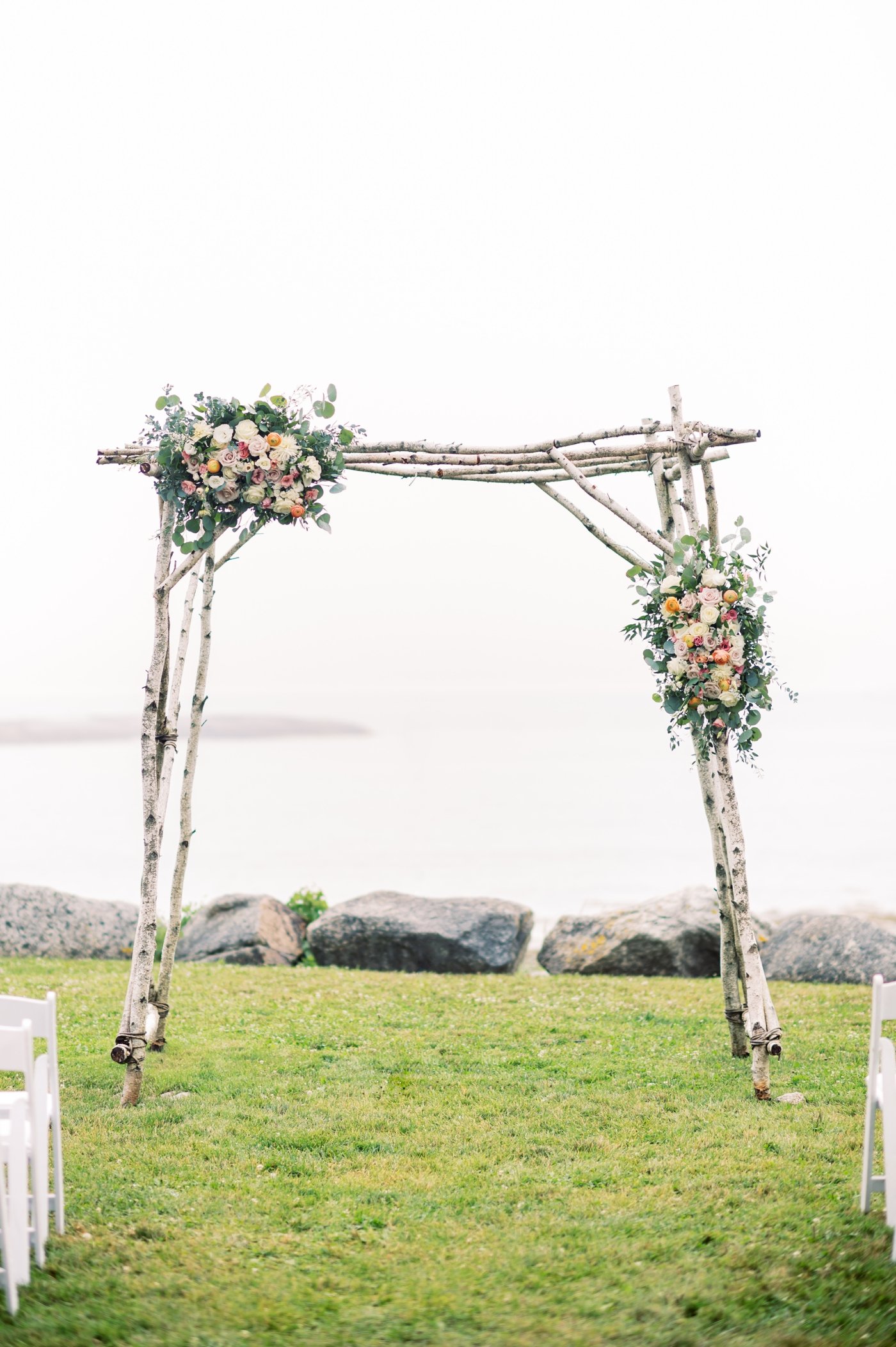 Birchwood wedding arch with eucalyptus and pink flowers at a seaside wedding ceremony