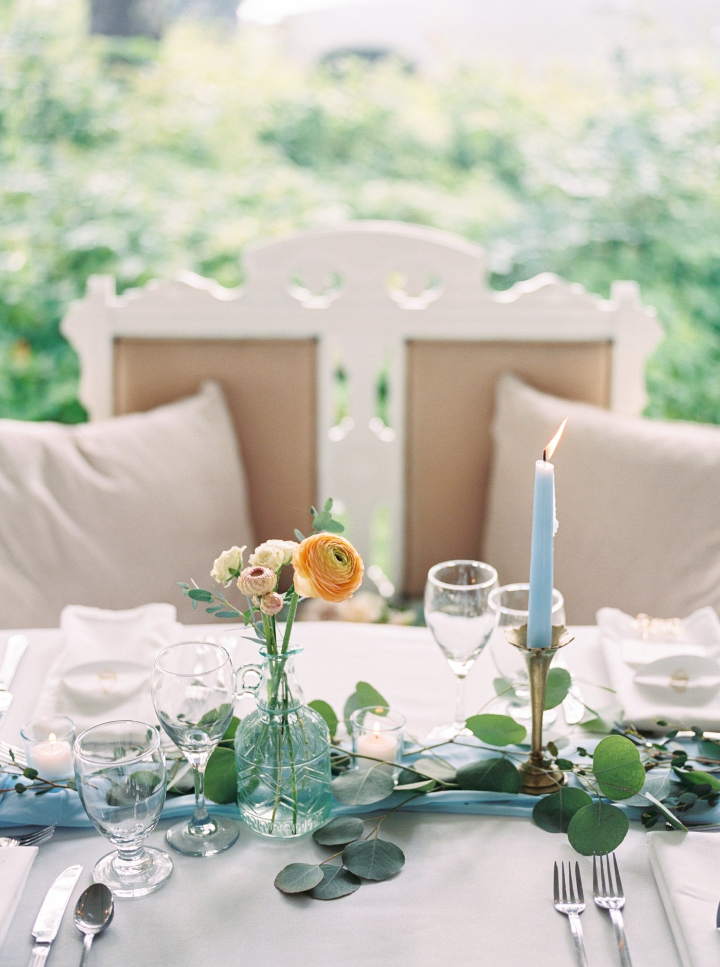 Elegant sweetheart table with bench, blue taper candle, and peach flowers