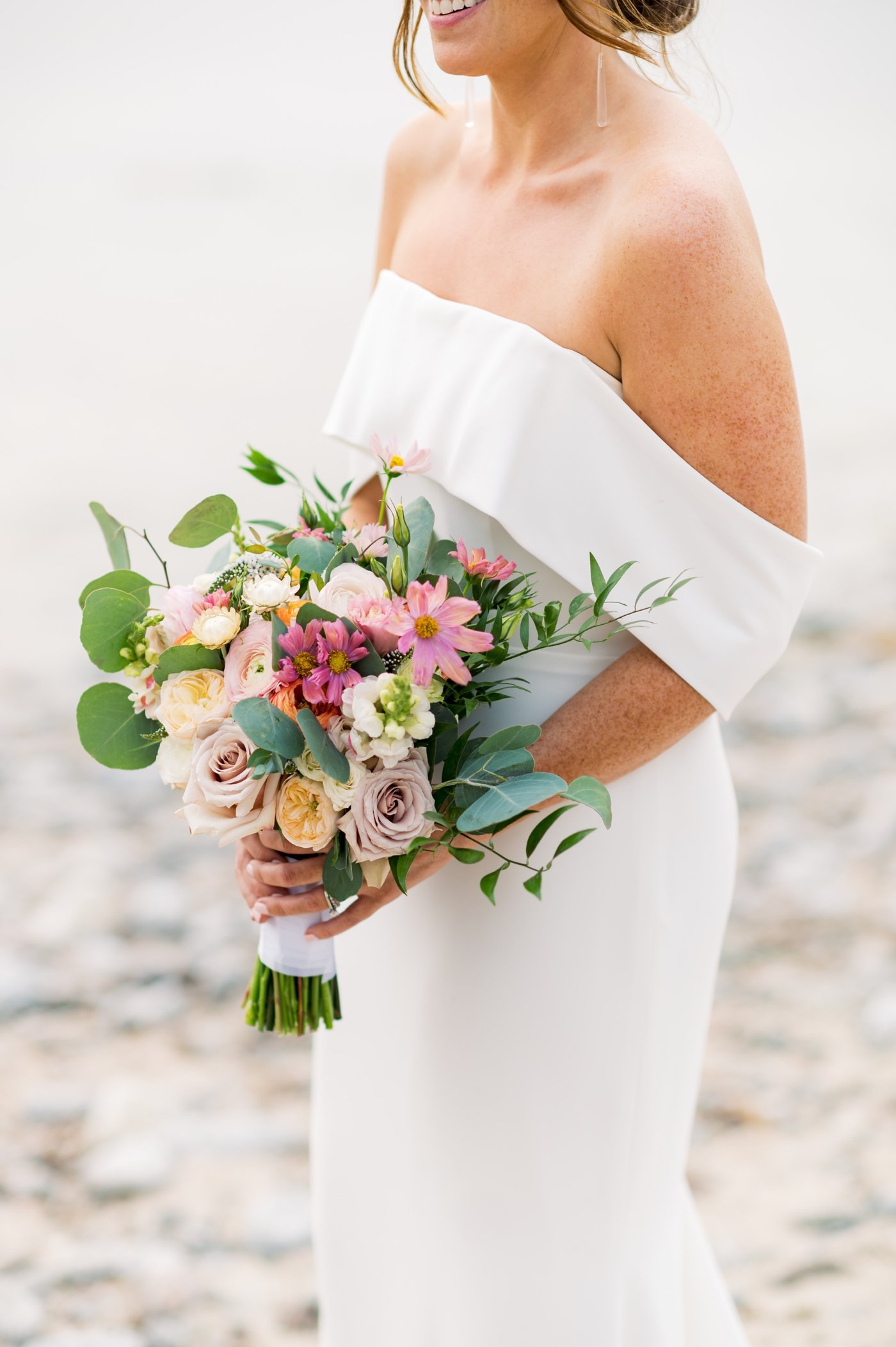 Bridal bouquet filled with blush roses, peach ranunculus, and white delphinium by A Beautiful Wild