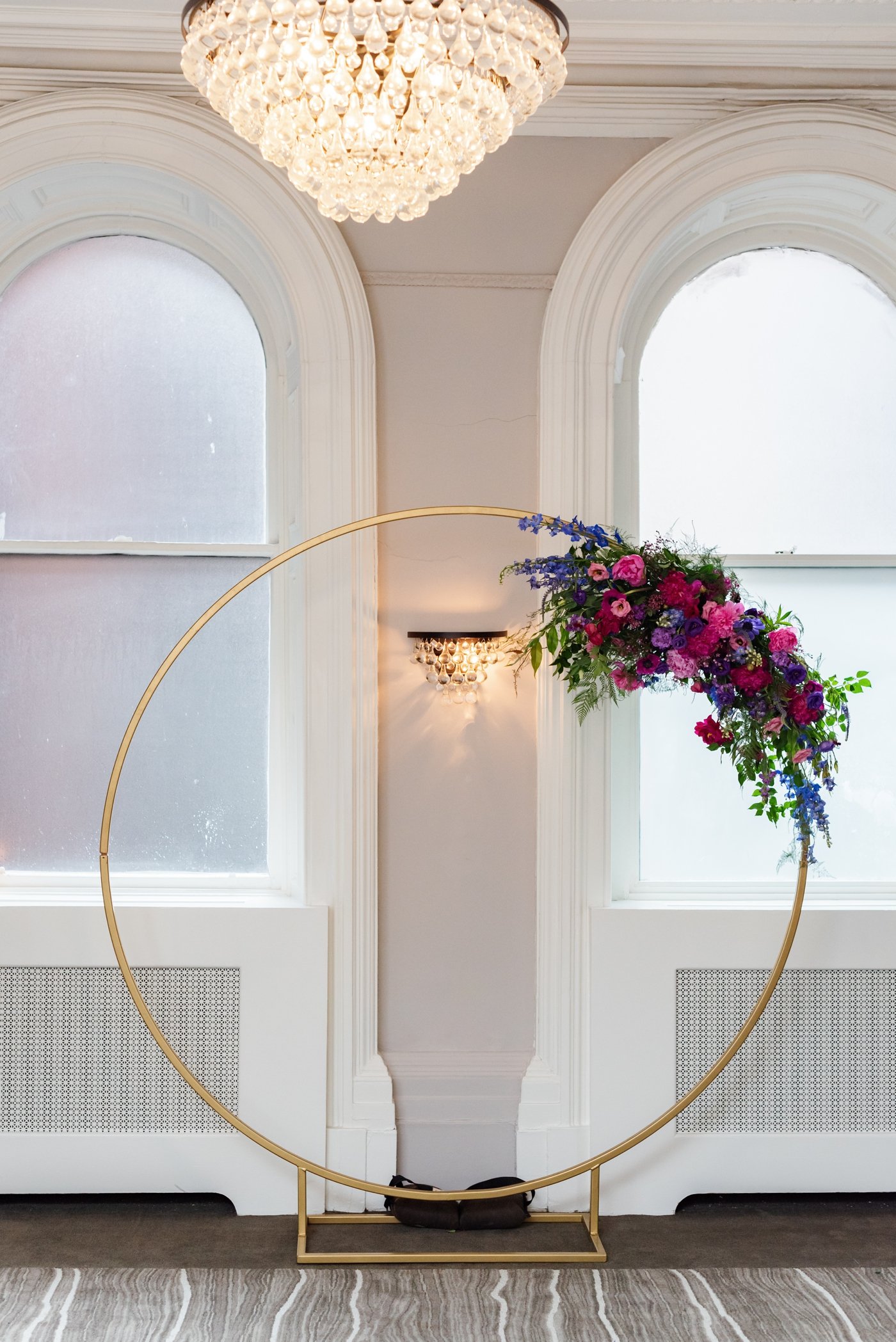 Circular gold wedding arch with purple and pink flowers