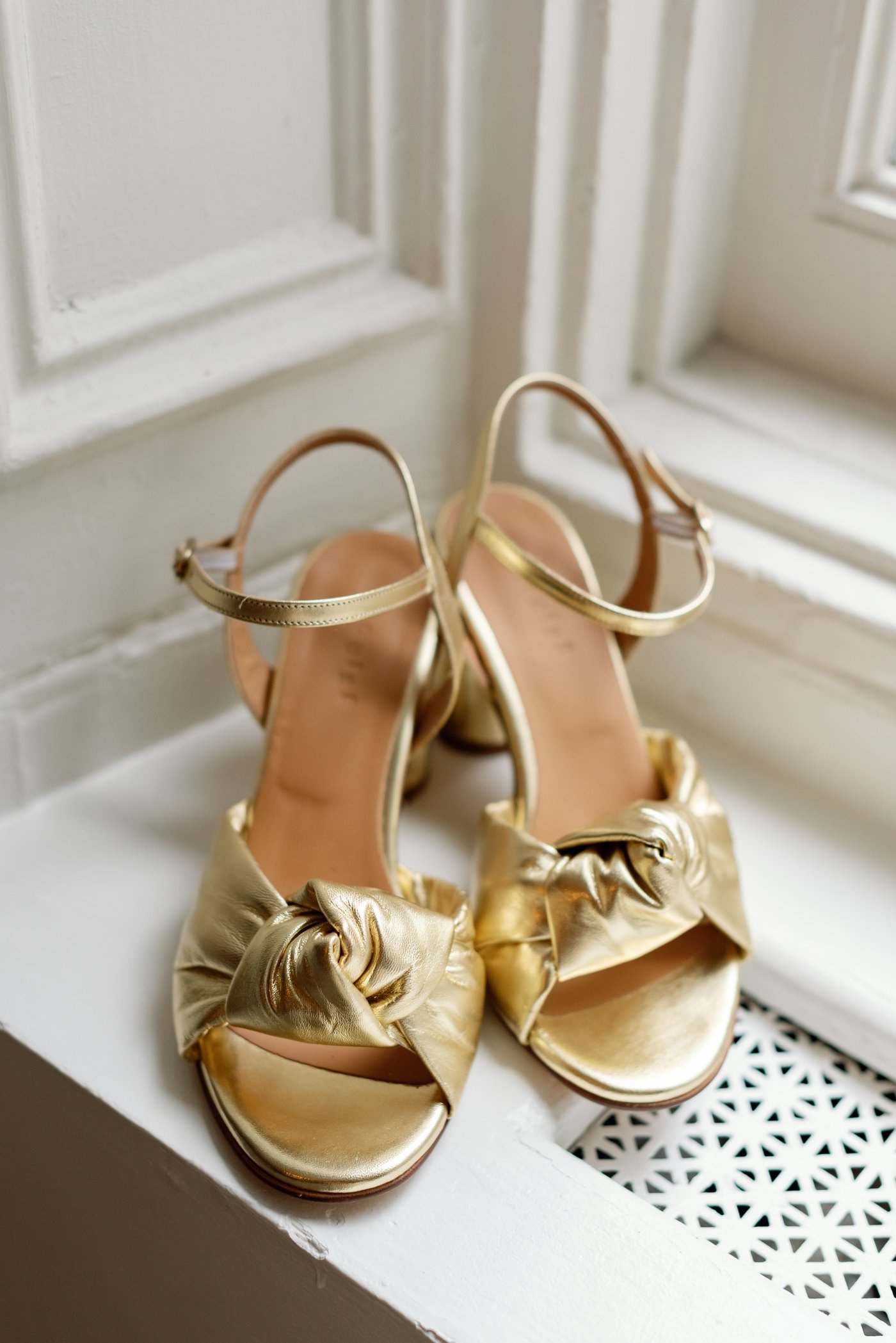 Gold bridal shoes on a windowsill