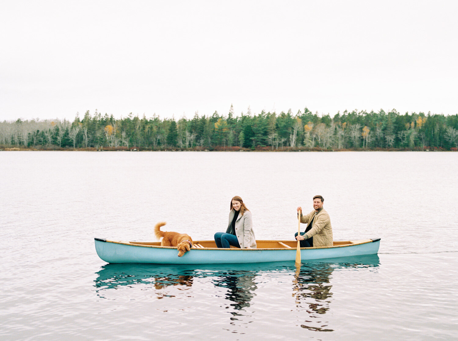 Couple with their dog in a blue canoe on a lake
