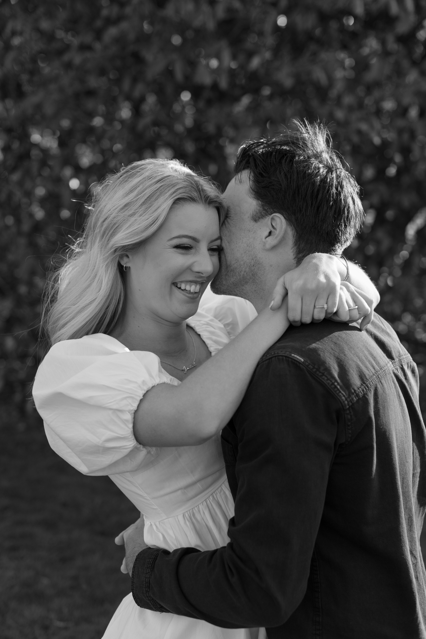 Black & white photo of engaged couple hugging and laughing