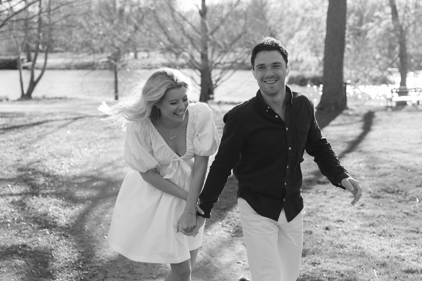 Black & white photo of engaged couple laughing in Halifax Public Gardens
