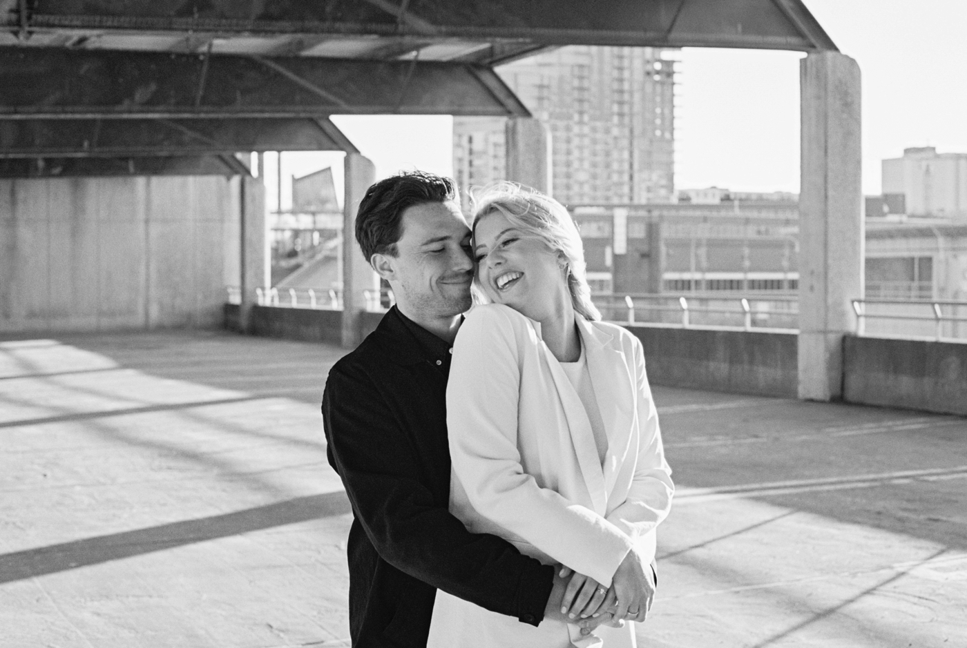 Black & white film photo of couple hugging and laughing in Halifax parking garage