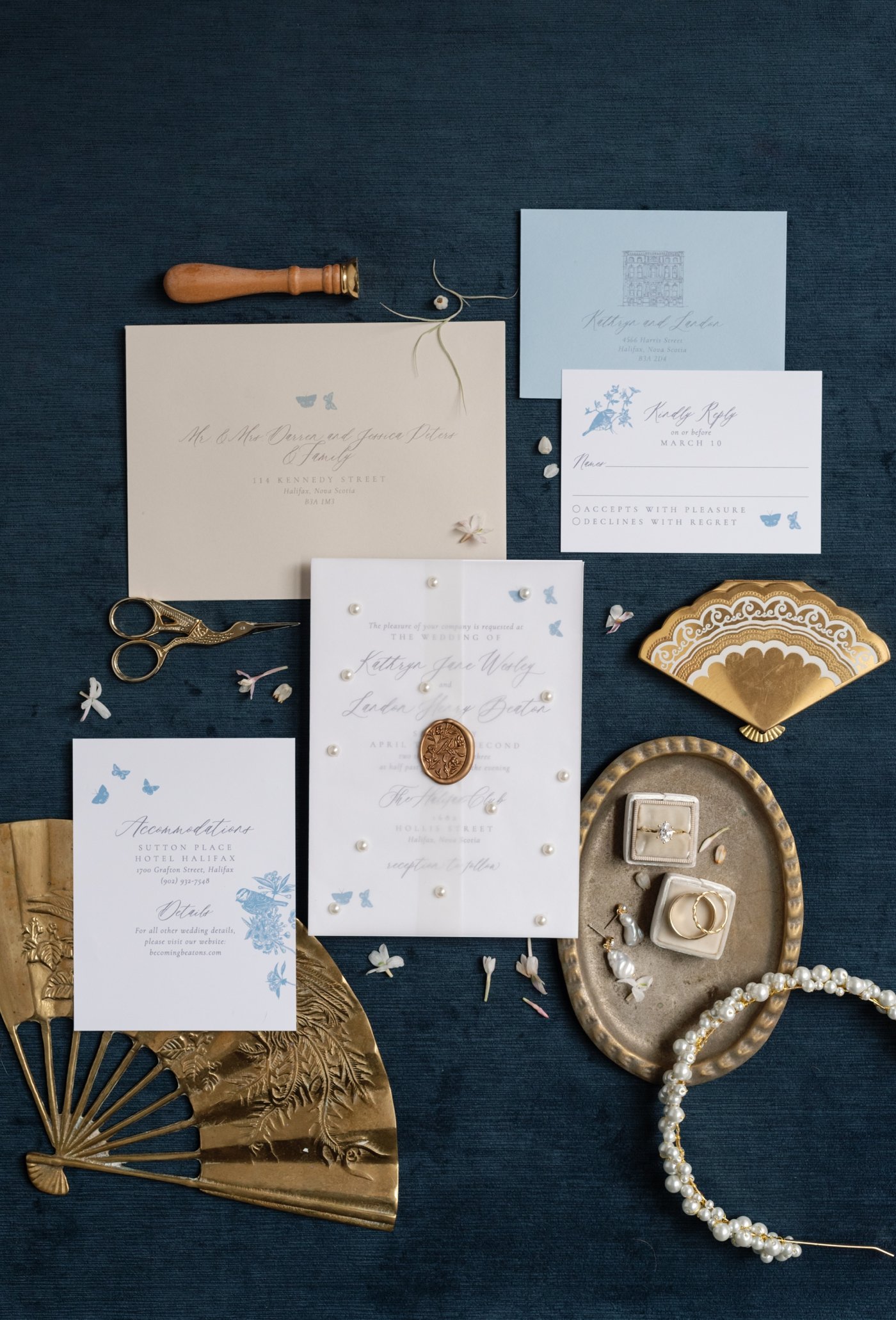 Flatlay of a chinoiserie inspired wedding invitation suite with pearl details and a gold wax seal
